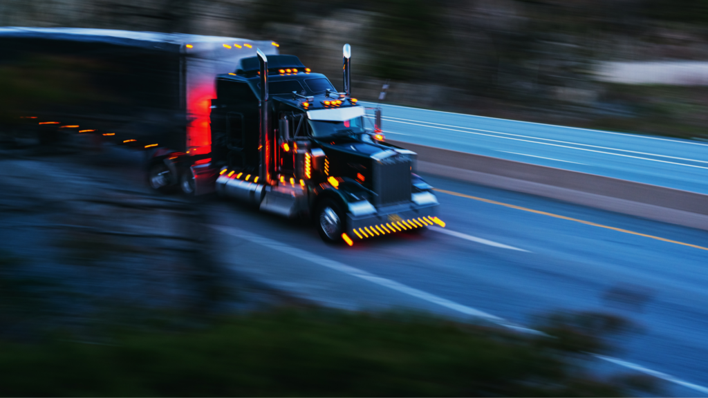 a semi truck driving on the interstate at night